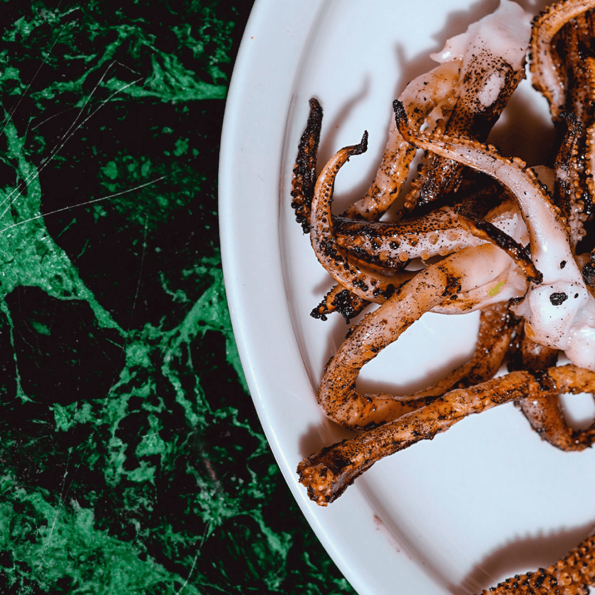 Squid in a white plate on a green background.